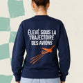 Dos d'un chandail crewneck bleu marine avec avion orange illustre et le message Eleve sous la trajectoire des avions, boutique Sans Filtre