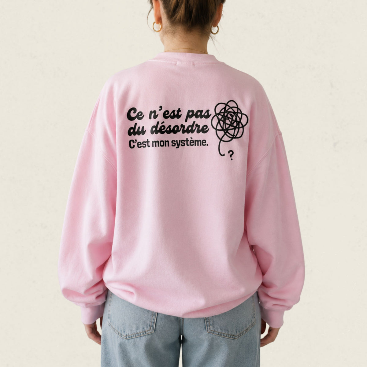 Dos d'un chandail crewneck rose avec gribouillis illustre et le message Ce n'est pas du desordre, c'est mon systeme, boutique Sans Filtre