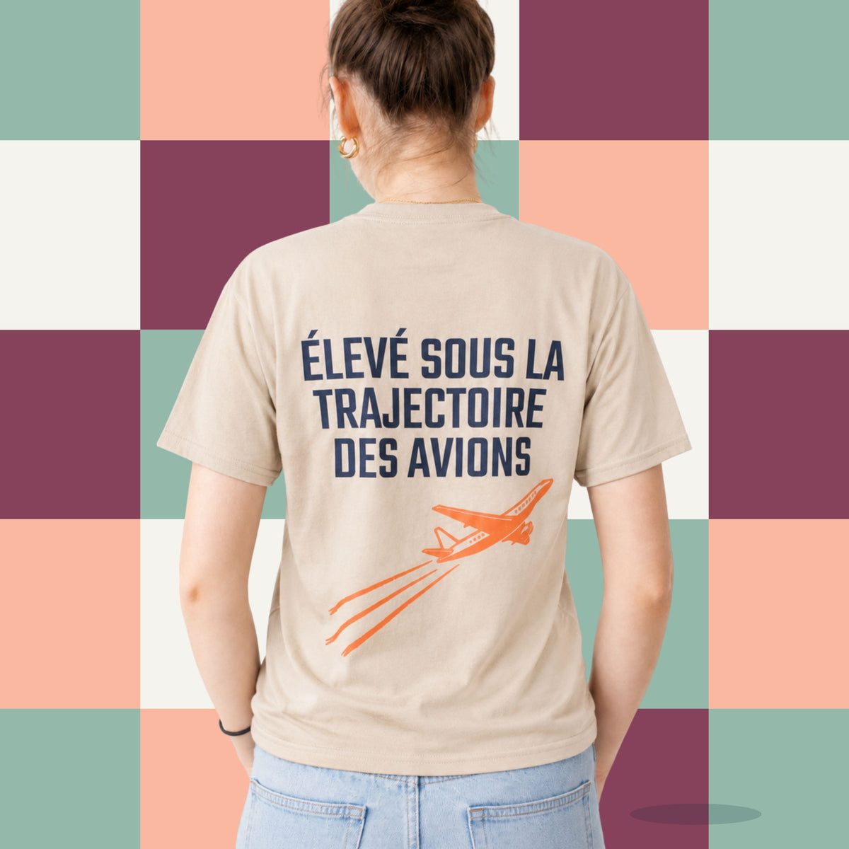 Dos d'un t-shirt sable avec avion orange illustre et le message Eleve sous la trajectoire des avions, boutique Sans Filtre