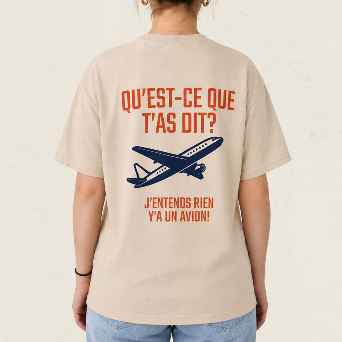 Dos d'un t-shirt sable avec avion illustre et le message Qu'est-ce que t'as dit, j'entends rien y'a un avion, boutique Sans Filtre